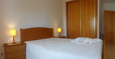 a bedroom with a bed and two lamps and a door at Apartamento Avenida da Liberdade in Albufeira