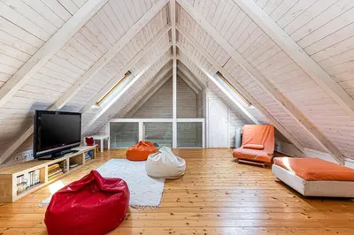 an attic living room with a tv and orange chairs at Villa Oliva - Maison 6 chambres in Vilamoura