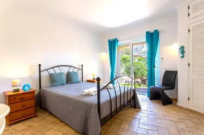 a bedroom with a bed and a chair and a window at Villa Matibora by HelloVacations in Albufeira