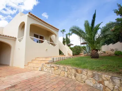 a white house with a stone wall next to a yard at Villa Matibora by HelloVacations in Albufeira