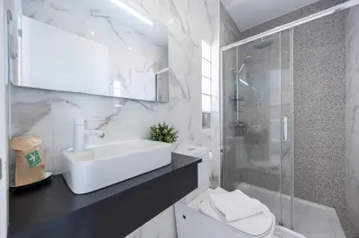 a white bathroom with a sink and a shower at Casa Verde Vilamoura in Quarteira