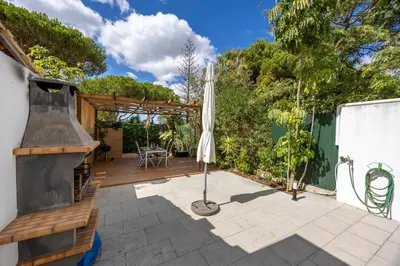 an outdoor patio with an umbrella and an outdoor grill at Casa Verde Vilamoura in Quarteira