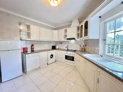 a kitchen with white appliances and a large window at Vilamoura White House Villa With Pool by Homing in Vilamoura
