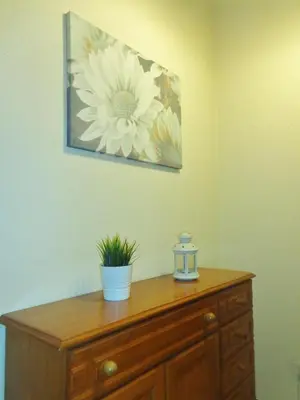 a wooden dresser with a flower painting on the wall at Apartamento Praia dos Salgados in Albufeira
