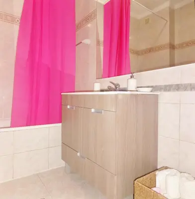 a bathroom with a sink and a pink shower curtain at Apartamento Praia dos Salgados in Albufeira