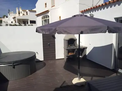 an outdoor grill with an umbrella on a patio at Casa com 3 suites, jacuzzi , en Albufeira in Albufeira