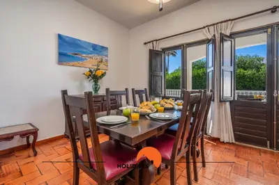 a dining room with a table and chairs and windows at #232 Vila Girasol 33 by Home Holidays in Albufeira