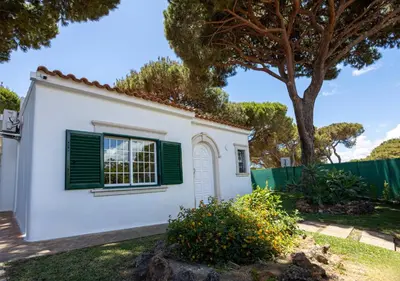 a white house with green shutters and a tree at Villa Moura by HelloVacations in Loulé