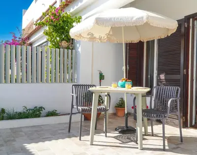 a table and chairs under an umbrella on a patio at Pilar Apartment in Albufeira