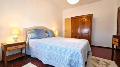 a bedroom with a bed and a wooden cabinet at Apart Alfarrobinha - T2 - BY BEDZY in Tunes