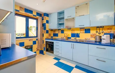 a kitchen with white cabinets and blue and yellow tiles at Romantic with private Hot Tub & Parking - big pool - Marina access in Albufeira