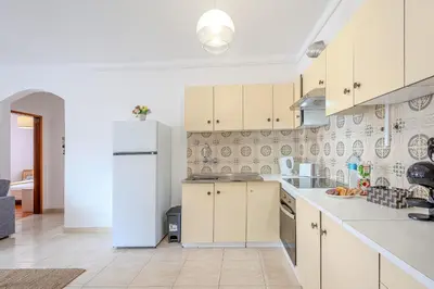 a kitchen with white cabinets and a white refrigerator at Apartamento Briza by Sunnyway in Albufeira