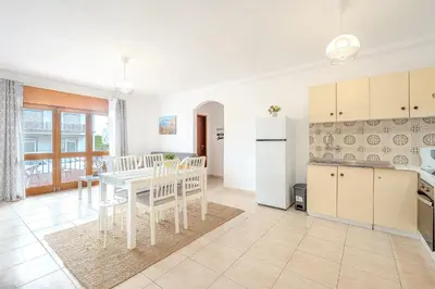 a kitchen and dining room with a white table and chairs at Apartamento Briza by Sunnyway in Albufeira