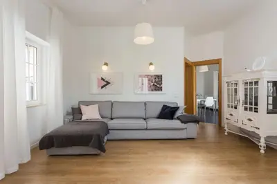 a living room with a gray couch in a white room at Charming house with terrace near the city center in Faro