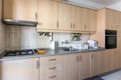 a kitchen with wooden cabinets and a sink at Color me Happy - 2 bedrooms apartment near Forum Algarve in Faro