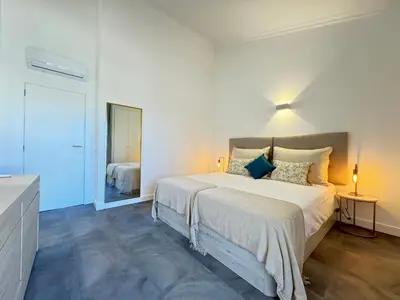 a white bedroom with a large bed and a mirror at Casa Coral Azul in Albufeira