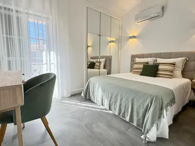 a white bedroom with a bed and a chair at Casa Coral Azul in Albufeira