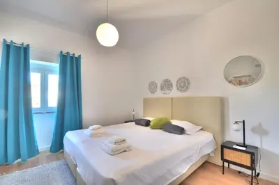 a bedroom with a large white bed with blue curtains at Old Town Gem by Atlantic Places in Albufeira