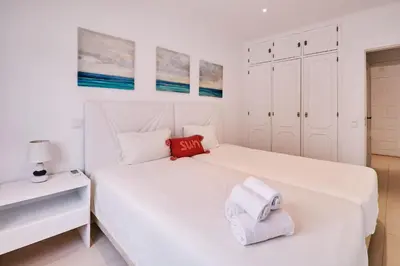 a white bedroom with a bed with towels on it at Apartment Monaco mit Pool in Albufeira