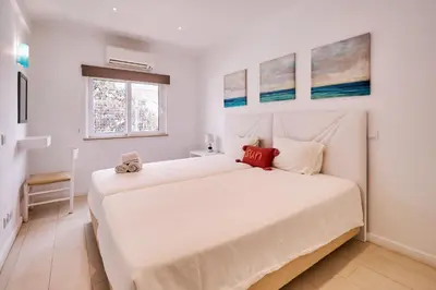 a white bedroom with two beds and a window at Apartment Monaco mit Pool in Albufeira
