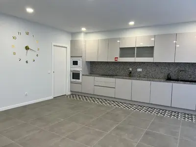 a kitchen with white cabinets and a clock on the wall at Casa MarRia in Faro