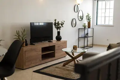 a living room with a flat screen tv on a wooden entertainment center at Oasis apartment - City center by HD in Faro