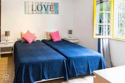two beds in a room with blue sheets and pink pillows at Sunshine Villa Salgados Guia Algarve in Albufeira