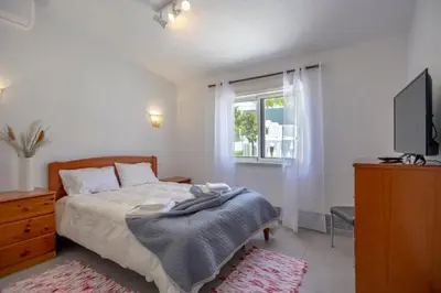 a bedroom with a bed and a tv and a window at Villa Le petit charme in Albufeira