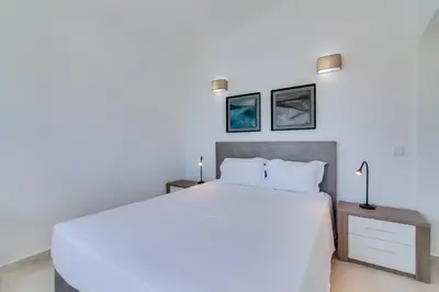 a bedroom with a white bed and two pictures on the wall at Villa Andorra, private pool next to golf in Vilamoura
