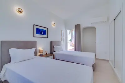 a white bedroom with two beds and a window at Villa Andorra, private pool next to golf in Vilamoura