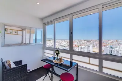 a room with windows and a table and chairs at 2bdr Sea View Miravila Apartment in Quarteira in Quarteira