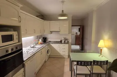 a kitchen with white cabinets and a table and a microwave at T3 - Casa Jerome in Quarteira