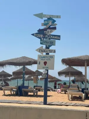 a street sign in front of a beach with umbrellas at T3 - Casa Jerome in Quarteira