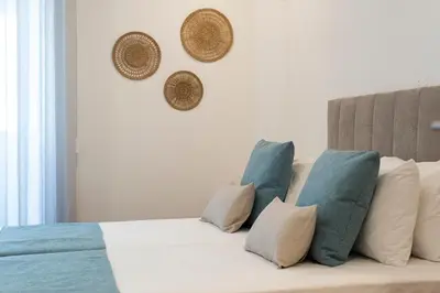 a white couch with pillows and hats on the wall at Madalena Hostel e Suites in Faro