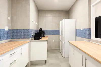a kitchen with white cabinets and a refrigerator at Madalena Hostel e Suites in Faro