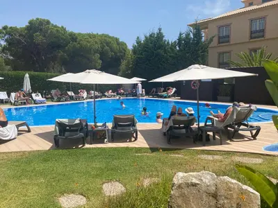 a pool with chairs and umbrellas and people swimming at Sunbliss - praia, piscina e localização central in Albufeira