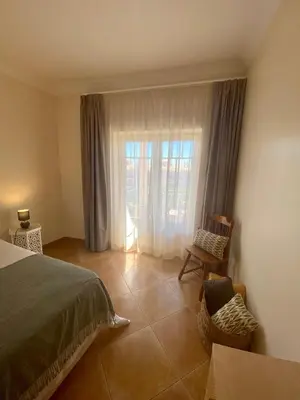 a bedroom with a bed and a chair and a window at Sunbliss - praia, piscina e localização central in Albufeira