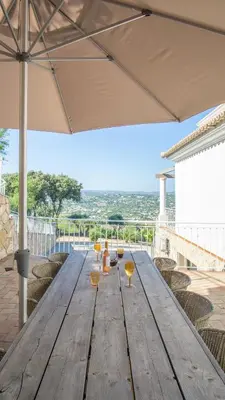 a wooden table on a deck with chairs and an umbrella at Casa Quadra Dique in Faro
