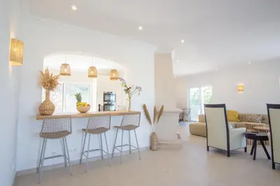 a kitchen and living room with a counter and stools at Casa Quadra Dique in Faro