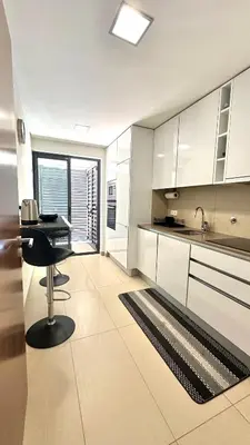 a kitchen with white cabinets and a table and a rug at Cavalo Preto Beach Resort in Quarteira