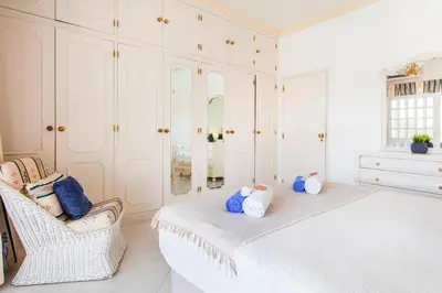 a white bedroom with a bed and a chair at Villa Paloma by Algarve Vacation in Albufeira