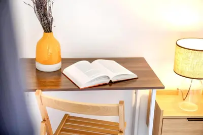 an open book on a wooden desk with a vase at Nap in the shade Apartment in Faro