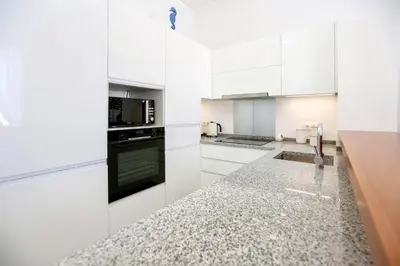 a kitchen with white cabinets and a counter top at Maison Faro Luxe - A Tranquil Retreat by the Algarve Coast in Faro