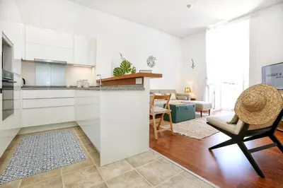 a kitchen with white cabinets and a chair in a room at Maison Faro Luxe - A Tranquil Retreat by the Algarve Coast in Faro