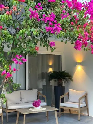 a group of chairs and tables under a tree with pink flowers at Casa Mocha Vale do lobo 2 bed apartment in Loulé