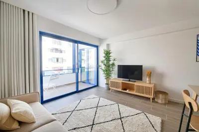 a living room with a couch and a tv at Amazing Flat, 100m from beach in Quarteira