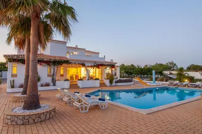 a house with a swimming pool and palm trees at Villa Serena by Algarve Vacation in Guia