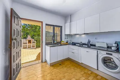 a kitchen with white cabinets and a washer and dryer at Villa Casa Jasmim by Villa Plus in Quarteira