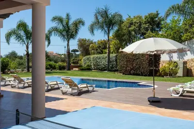 a swimming pool with chairs and an umbrella next to a pool at Villa Monte Avós by Ecovillas Albufeira in Albufeira