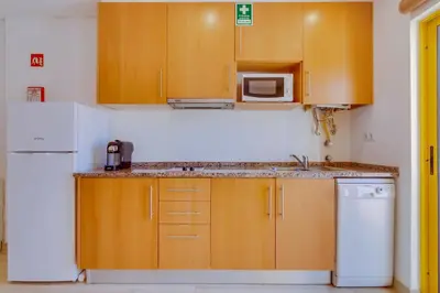 a kitchen with wooden cabinets and a sink and a microwave at Side Villas - 1bdr Retreat with BBQ & Patio in Quarteira